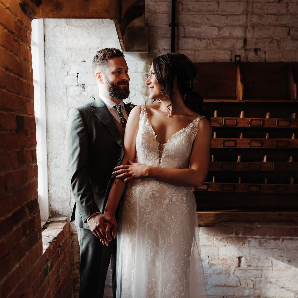 Bride in Madison James wedding dress with floral pattern smiling at the groom for couple portrait 
