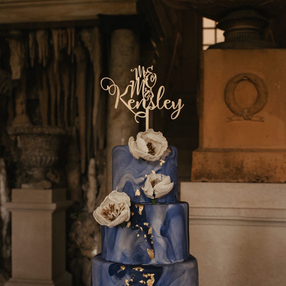 Four tier marble effect wedding cake with gold flakes and a gold cake topper 