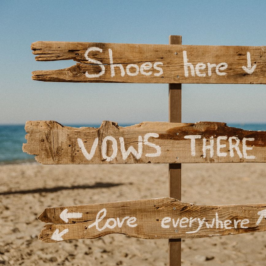Beach wedding signage that says 'Shoes here, vows there, love everywhere'