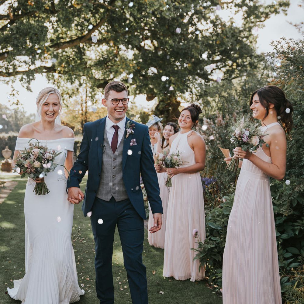 Bride & groom walk through friends and family with confetti being thrown around them