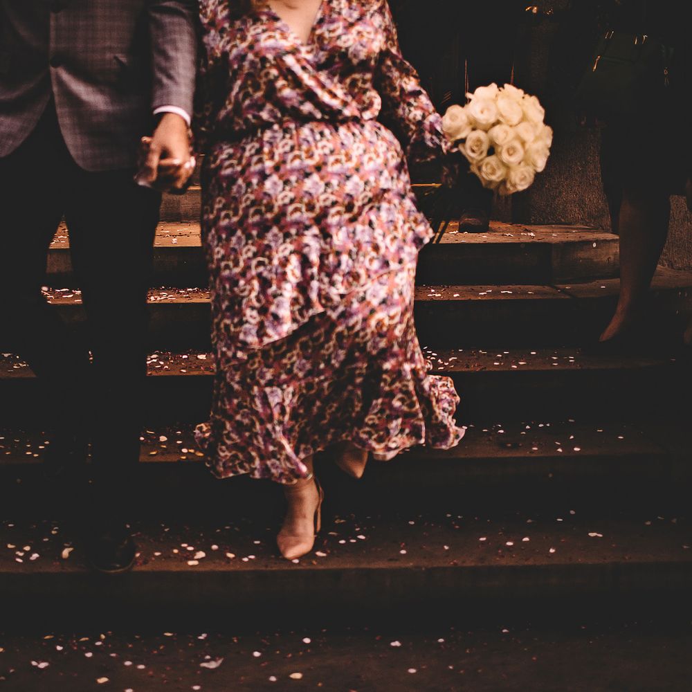 Bride & groom walk down steps with confetti at their feet after it has been thrown