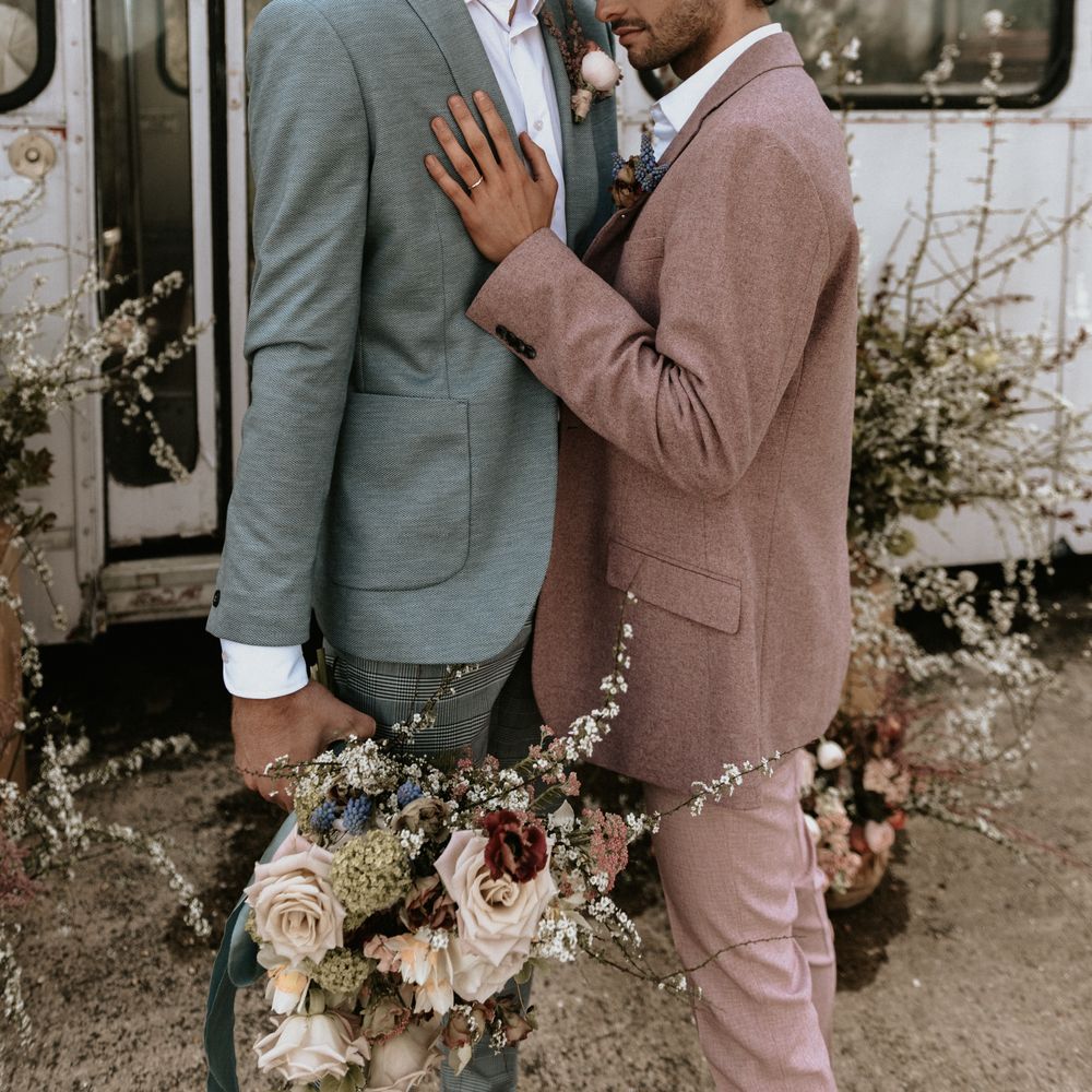 Groom leans into groom whilst stood outdoors at The Fire Pit Camp
