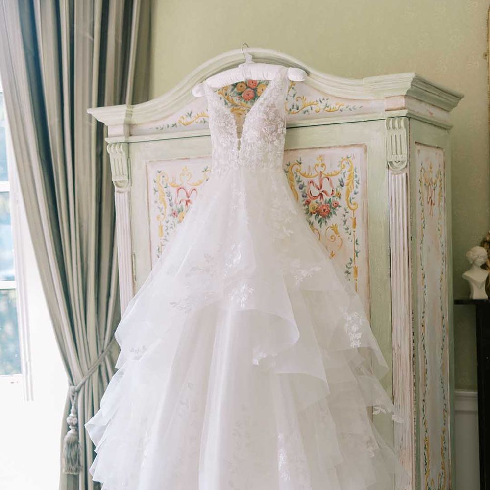 Layered tulle and lace Martina Liana wedding dress hanging on a wardrobe 