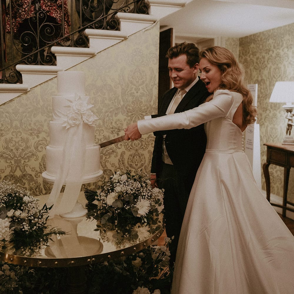 Bride and groom cutting large white semi naked wedding cake at Hedsor House wedding