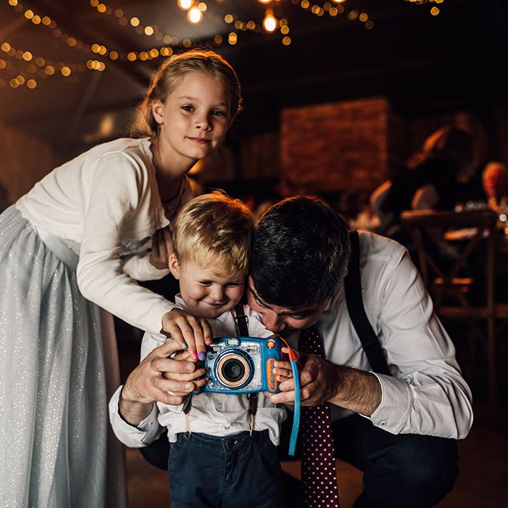Older wedding guest and younger wedding guest take a snap with toy camera 