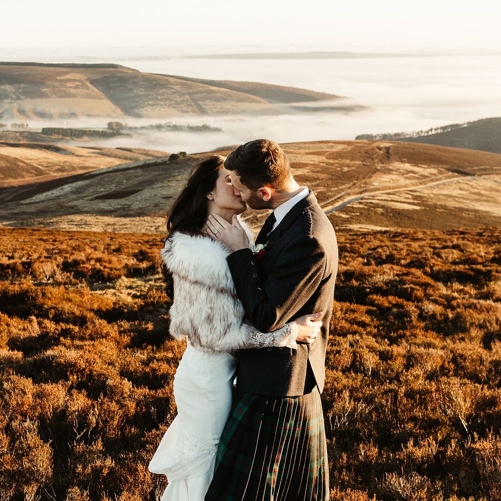 Bride & groom embrace on Scottish hills during sunset on their wedding day