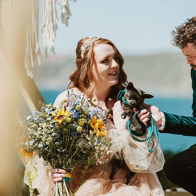 Bride & groom hold their pet dog for wedding day in Cornwall outdoors 