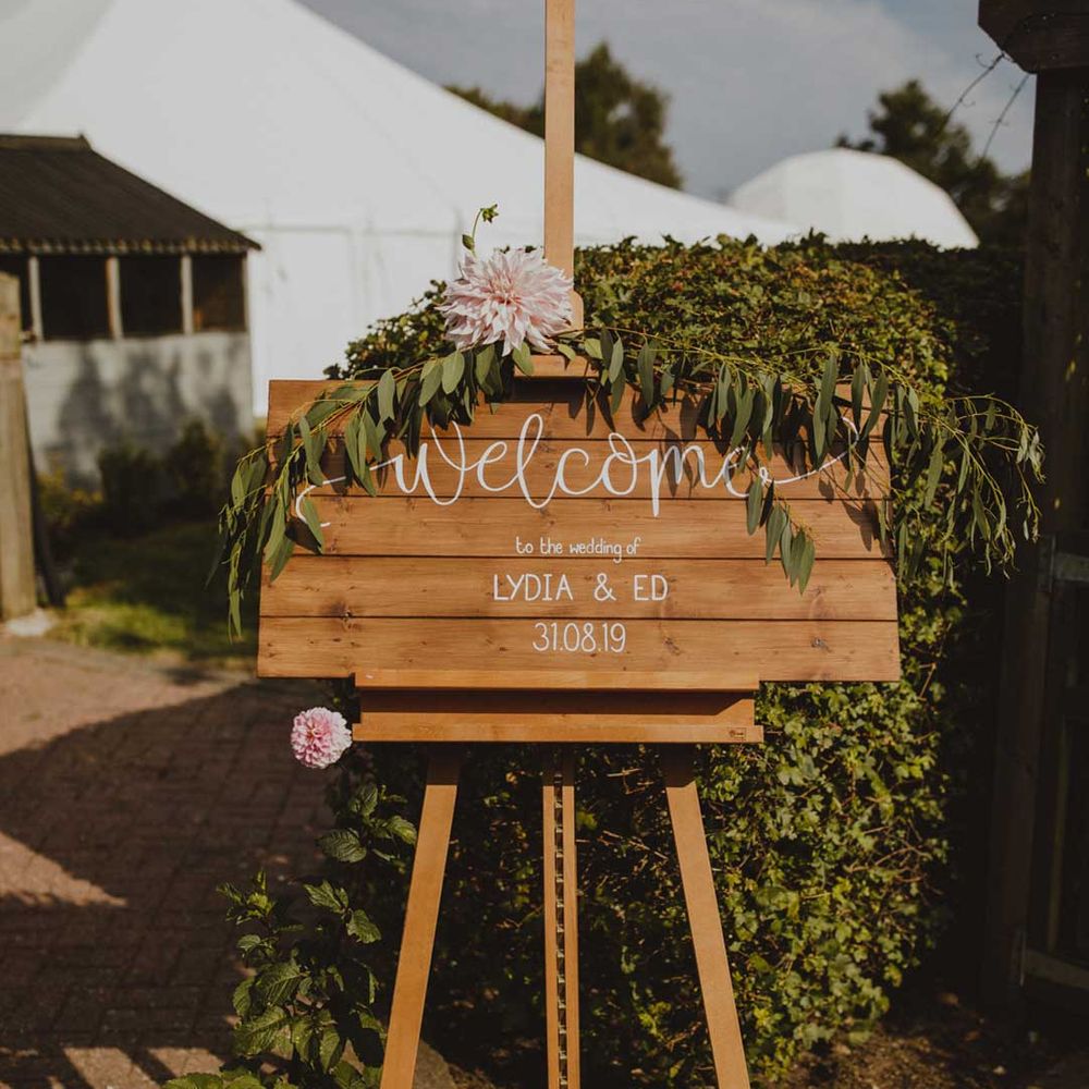 DIY wooden wedding welcome sign with fauna decorations and large pink flowers