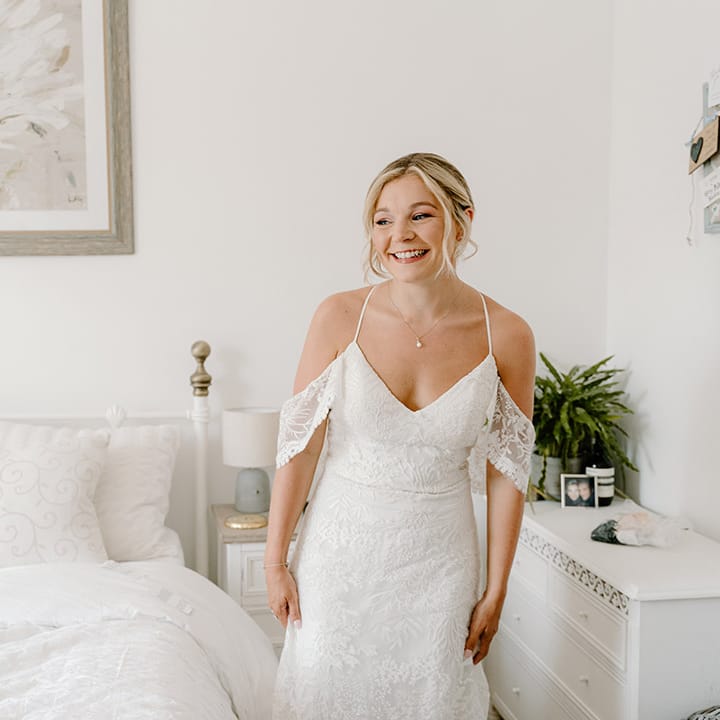 Blonde bride wears lace wedding dress with cold shoulder detailing and fitted style