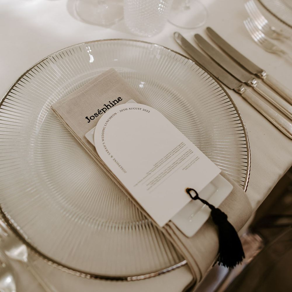 Silver striped and rimmed charger plates with personalised embroidered napkins and black and white wedding menus 