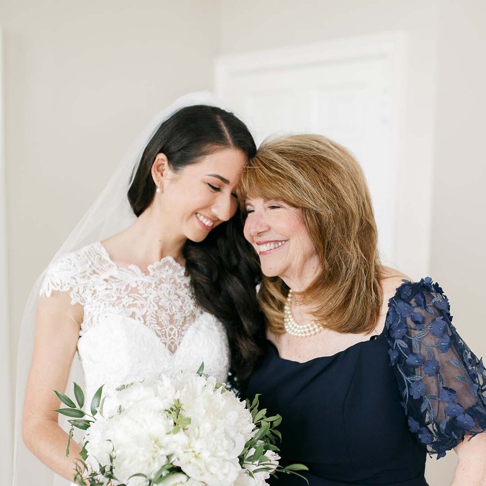 Bride in a Kelly Faetanini wedding dress with her mum in a navy mother of the bride dress with appliqué sleeves