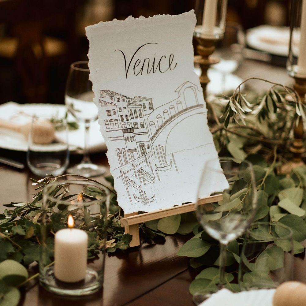 Venice illustrated table name surrounded by ecalyptus on wedding tablescape
