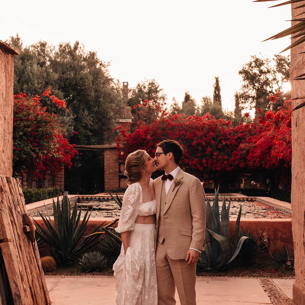 Bride in long sleeve lace crop top and skirt with the groom in three piece cream suit at their Morocco destination wedding 