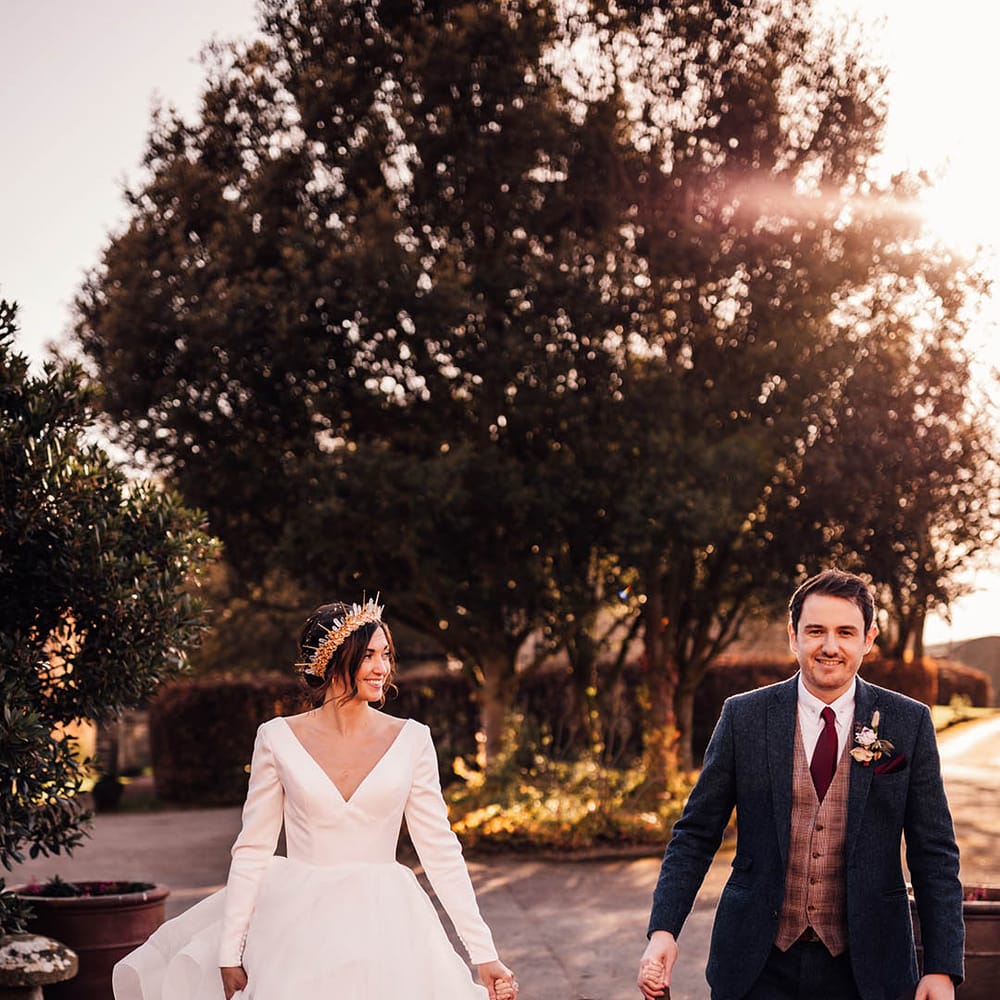 Groom in navy suit walking hand in hand with their son in a brown suit and bride in princess wedding dress and crown 
