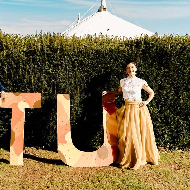 Bride in white mesh lace bridal crop top and yellow wedding skirt standing by large wedding decorations with groom in traditional Nigerian wedding outfit