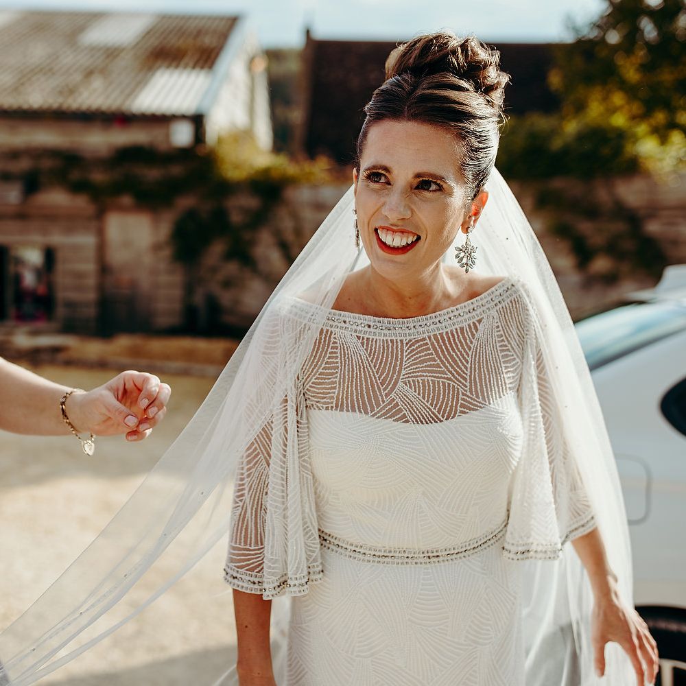 Bride wearing red lipstick with veil being carried
