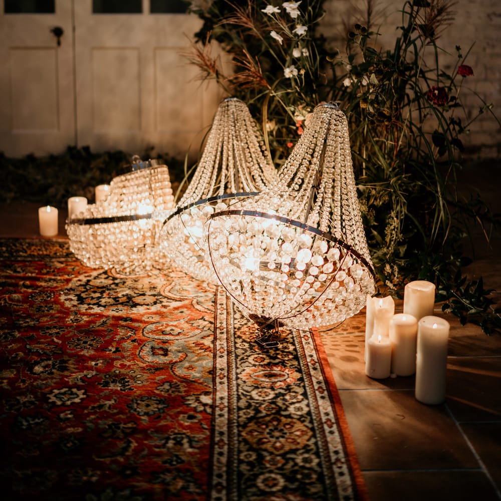 Chandlier's and pillar candles resting on a wool rug to create an intimate ambience in the Our Beautiful Glasshouse wedding venue