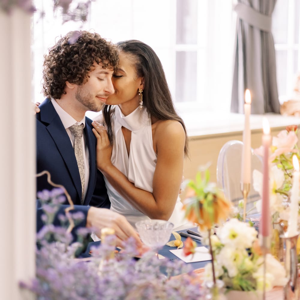 Bride leans in to kiss groom as she holds her hand to his shoulder