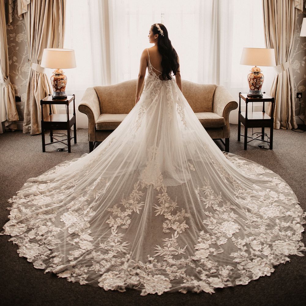 Bride portrait from behind at bay window with wedding dress train fanned out