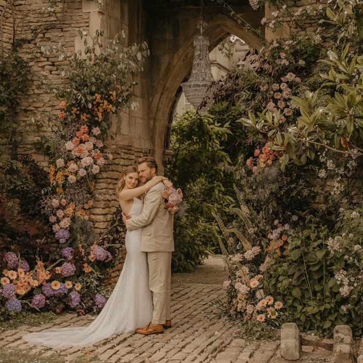Bride and groom portrait at Euridge Manor under the castle arch with chandelier and pastel coloured flowers 