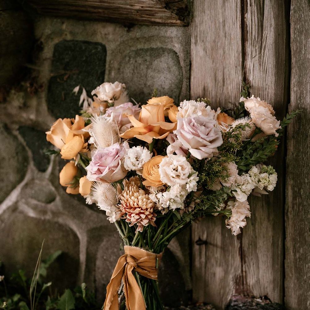 Wedding bouquet with blush pink and yellow peeled back roses tied with ribbon