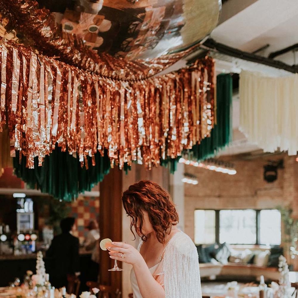 Bride holds cocktail during wedding reception