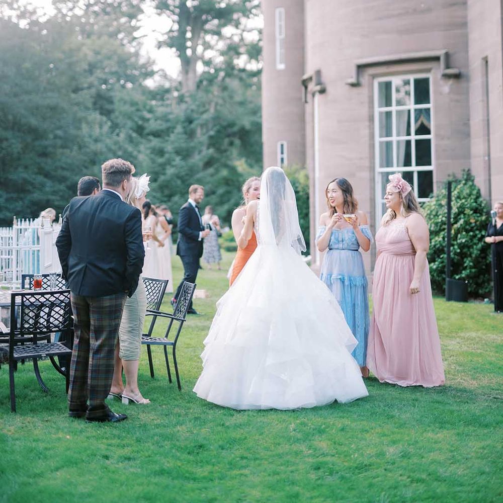 Bride in a Martina Liana princess wedding dress talking to wedding guests at her Drumtochty Castle wedding 