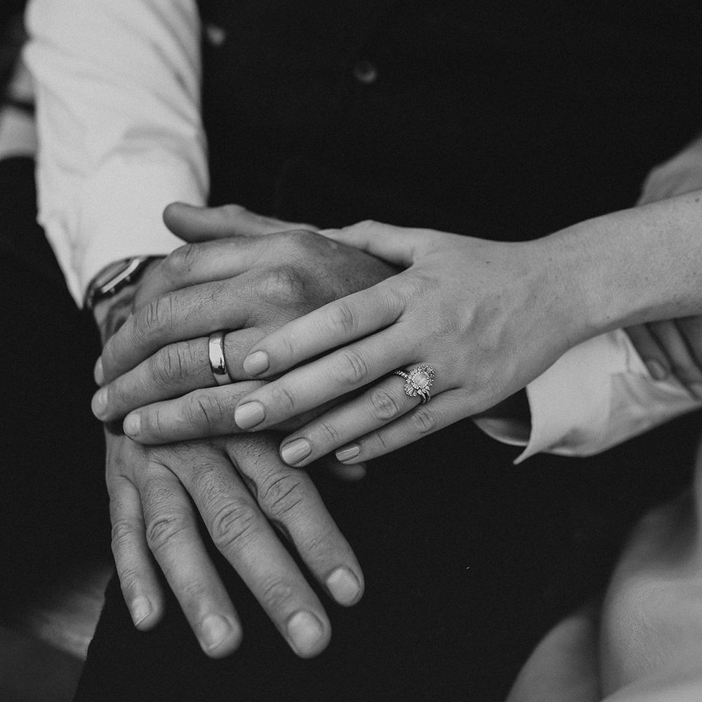 Bride and groom holding hands showing off their wedding and engagement rings 