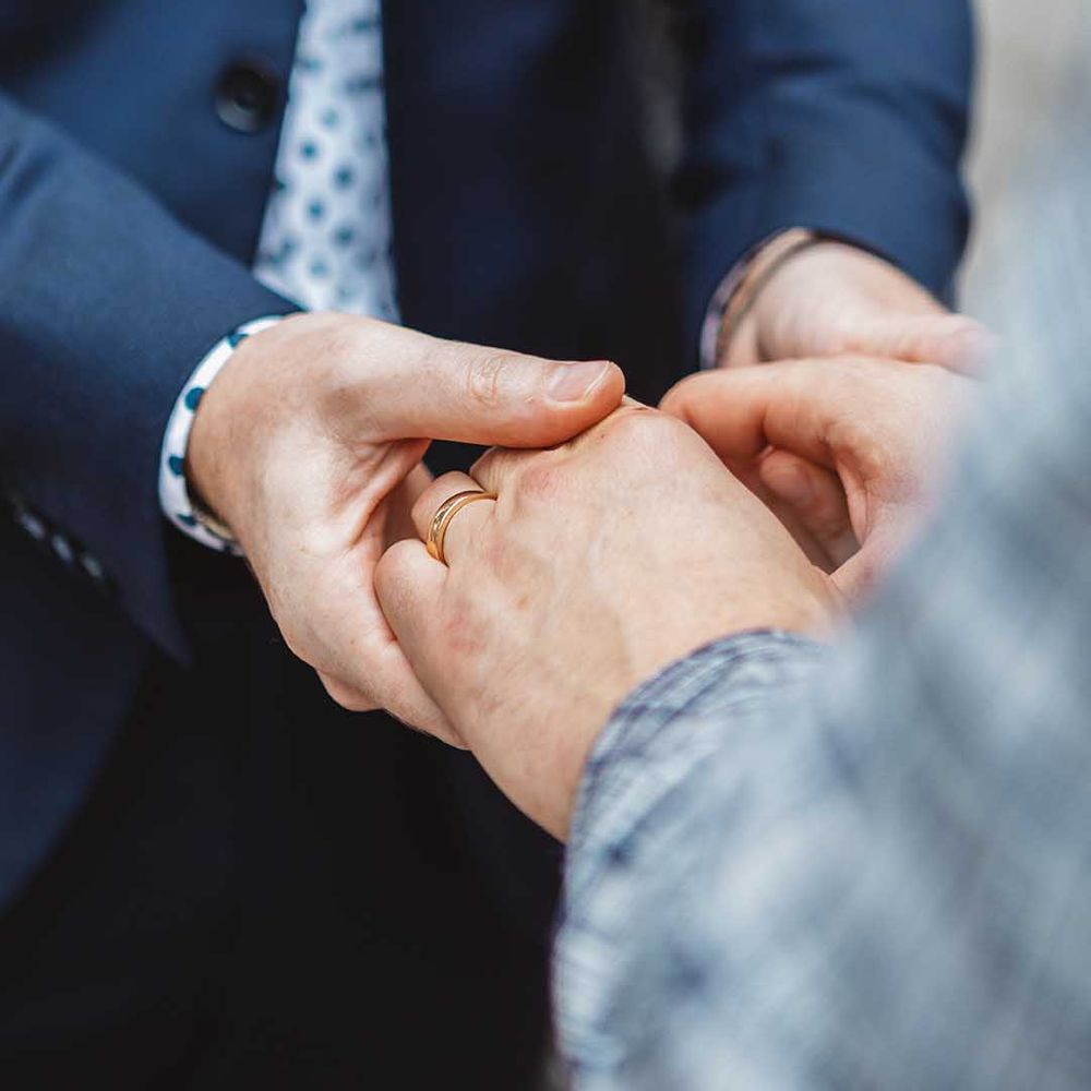 Grooms hold hands on their wedding day