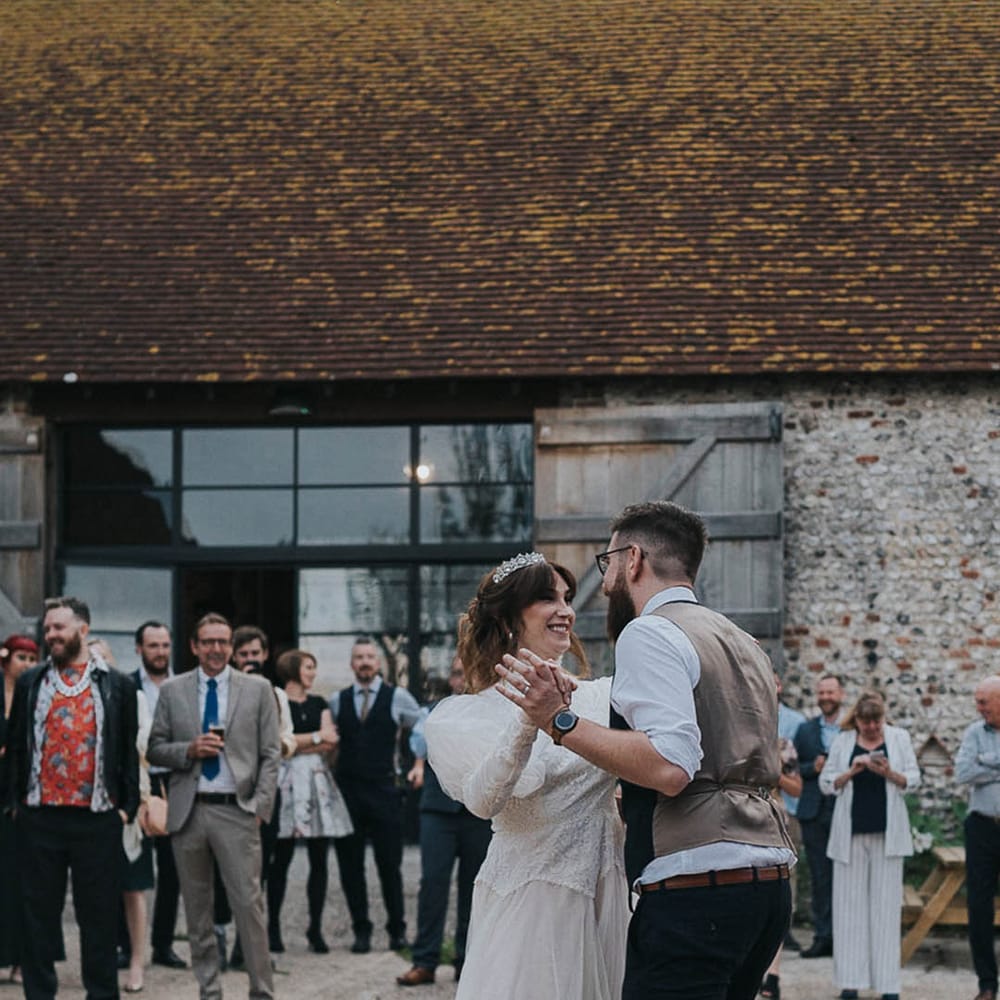 Newlyweds stand outdoors for first dance on their wedding day in rustic farm setting