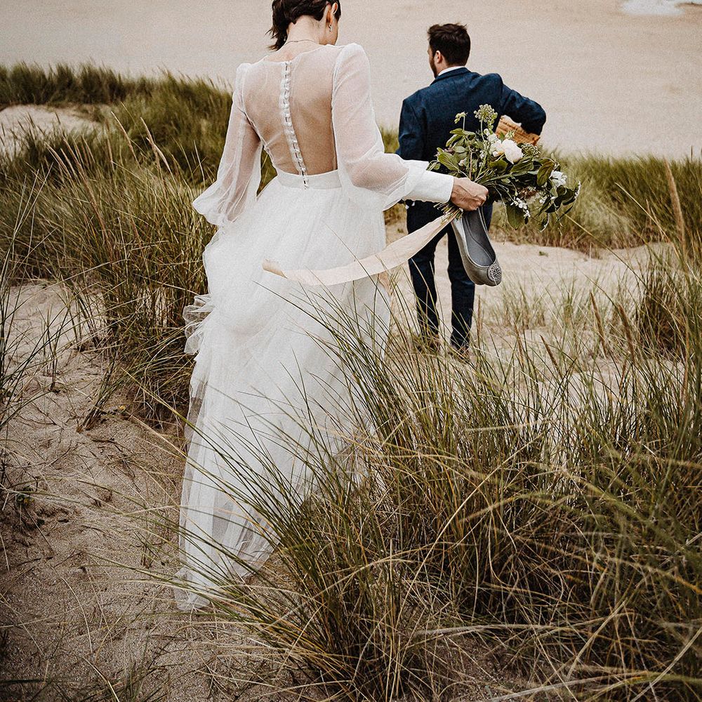 Bride and groom walk down onto the beach during their wedding day at Cornwall 