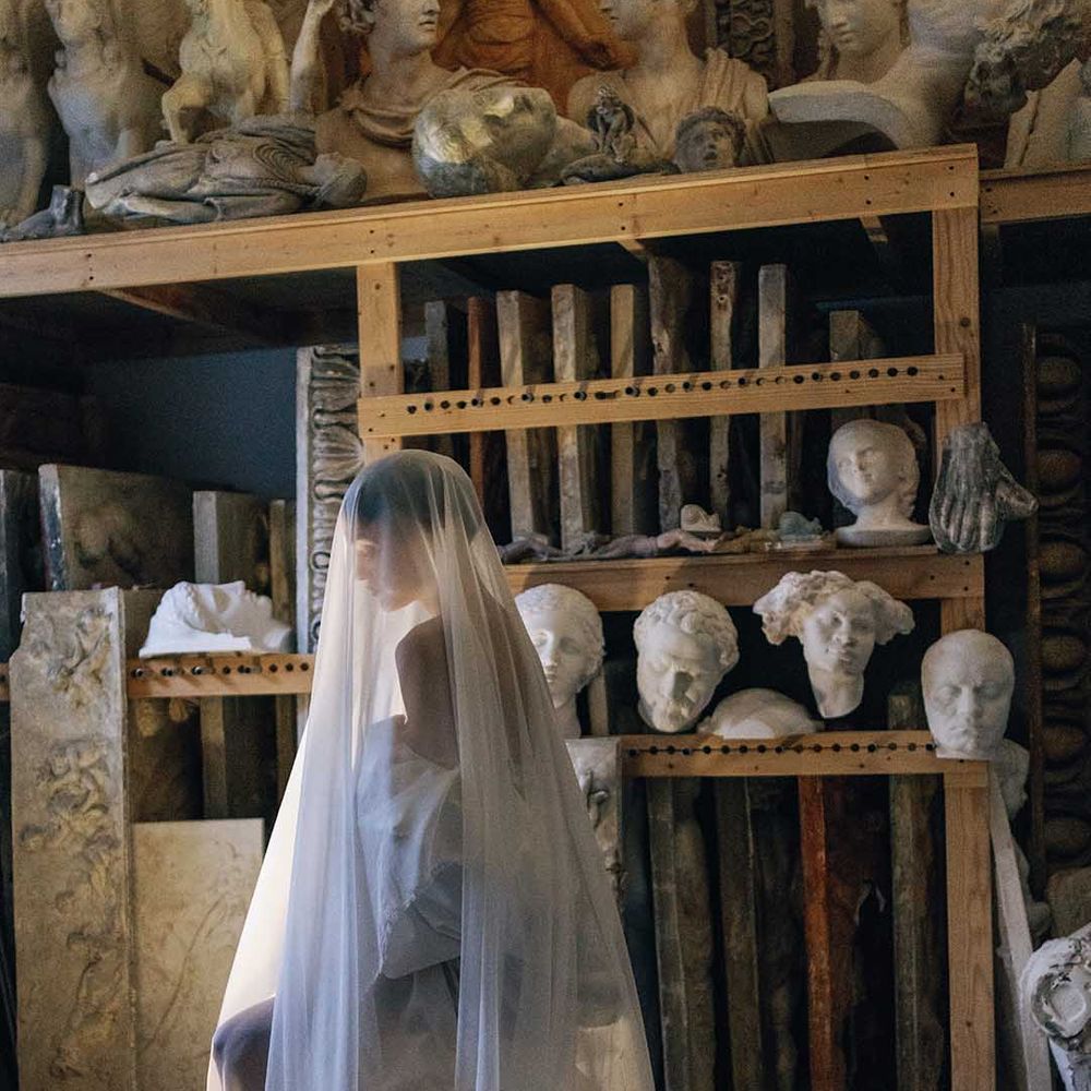 Bride sits wearing long veil covering her whole head and body