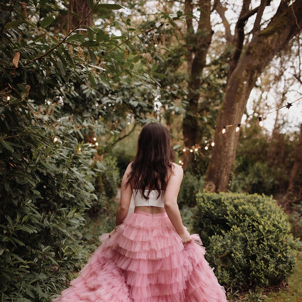 Bride with long wavy hair wearing a layered pink tulle wedding skirt in the gardens at Ballykealey House, Ireland 