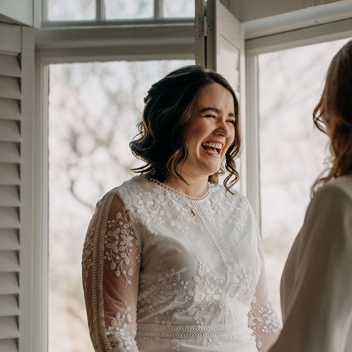 Bride looks lovingly at her wife on her wedding day whilst wearing boho gown from Coast 