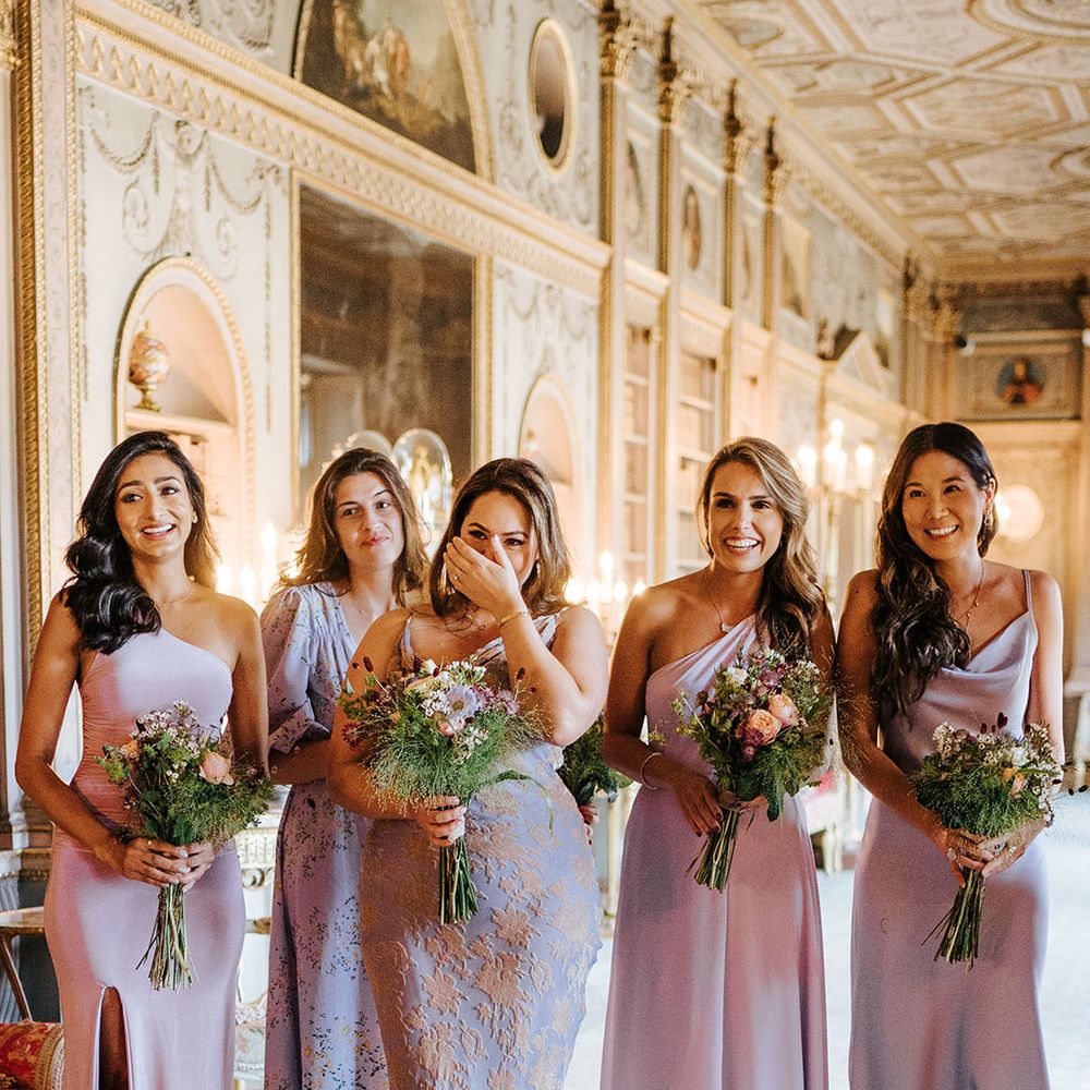 Bridesmaids wearing lavender bridesmaid dresses in differing shades and styles see bride for the first time 