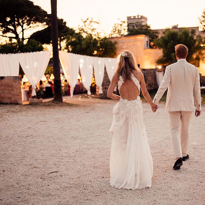 Bride in a flower Emma Beaumont wedding dress walking with the groom at their destination wedding 