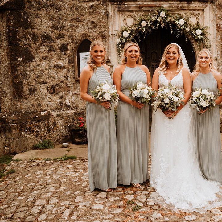 Bridesmaids in sage green halter neck pleated bridesmaid dress with the bride in a flower lace gown 