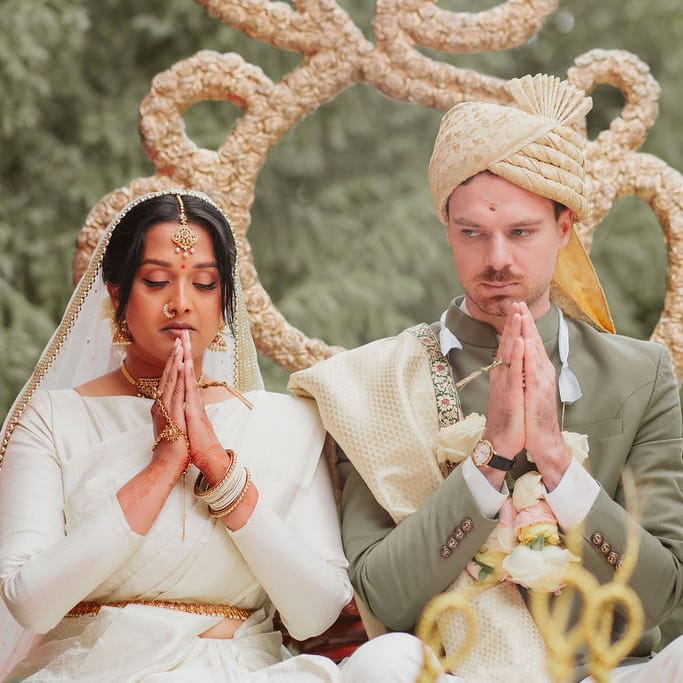 Bride in a cream Lehenga and groom in a green and gold Sherwani at Hindu wedding ceremony 