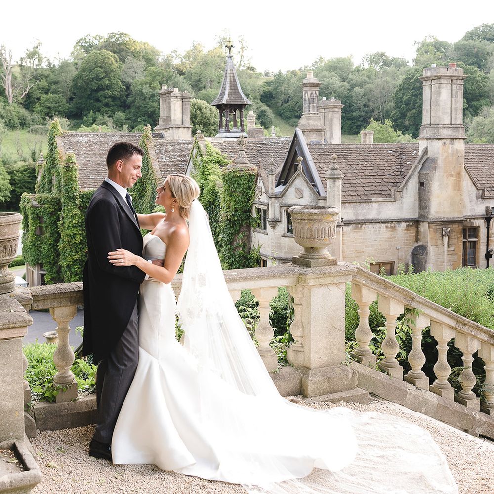 Bride in fitted mermaid Pronovias wedding dress with the groom in morning suit for wedding at The Manor House, Castle Combe wedding venue 
