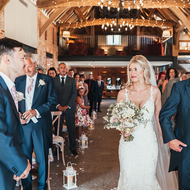 The father of the bride walks the bride down the aisle to meet the groom at Rackleys Chiltern Hills barn wedding venue 