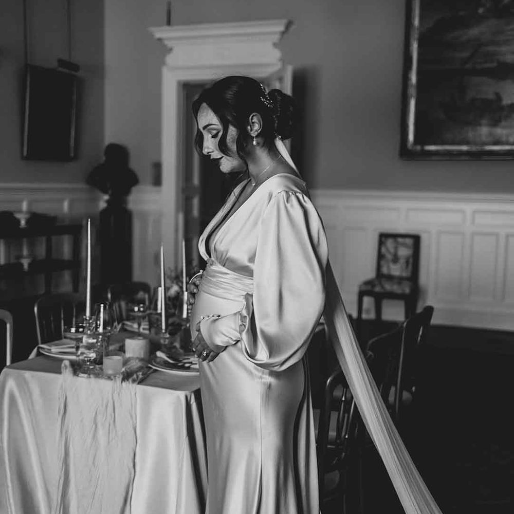 pregnant bride in a satin wedding dress with long sleeves 