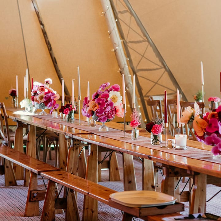 Pink, peach and white wedding taper candles with flower table arrangements at tipi wedding