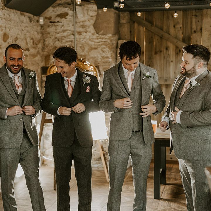 Groomsmen in matching light grey suits standing with the groom 