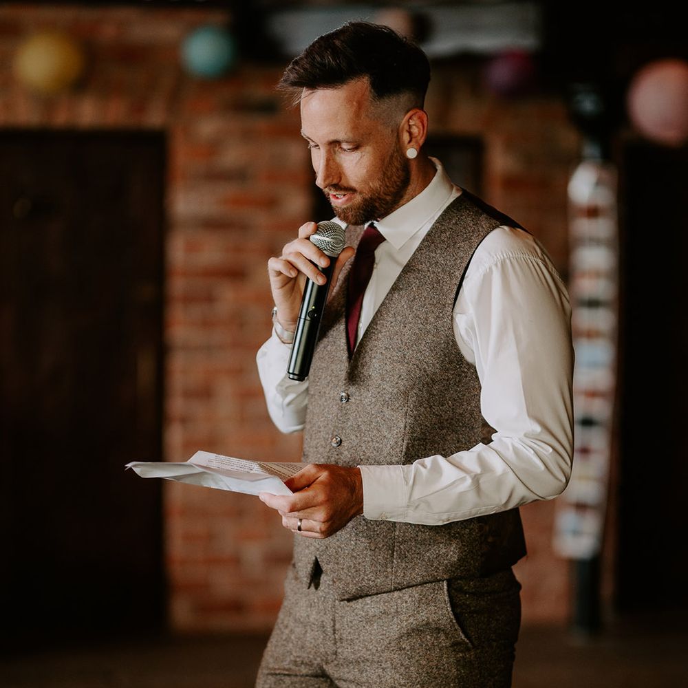 Groom stands with a microphone to read out his wedding speech 