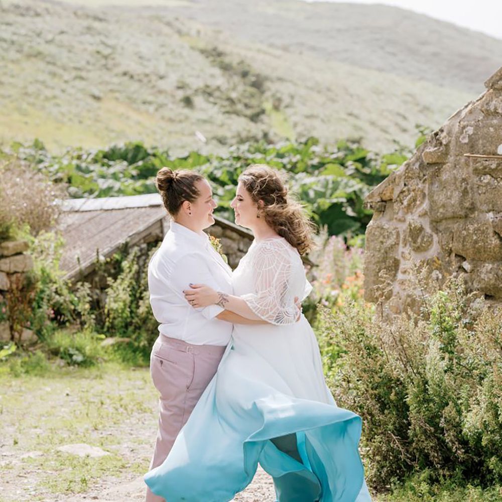 Two brides at LGBTQI wedding with the bride wearing a white and blue ombre colourful wedding dress 