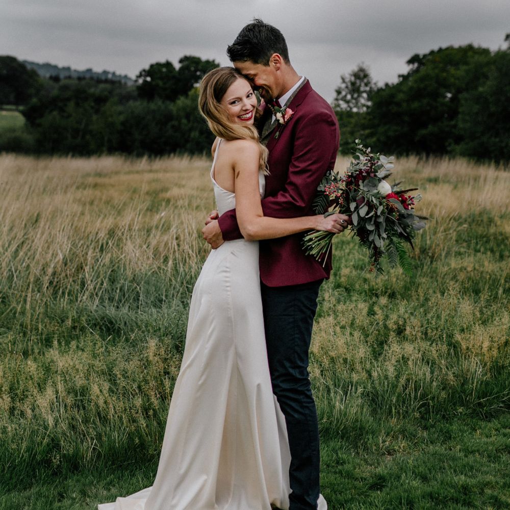 Bride and groom embracing in a field at High Billinghurst Farm micro wedding