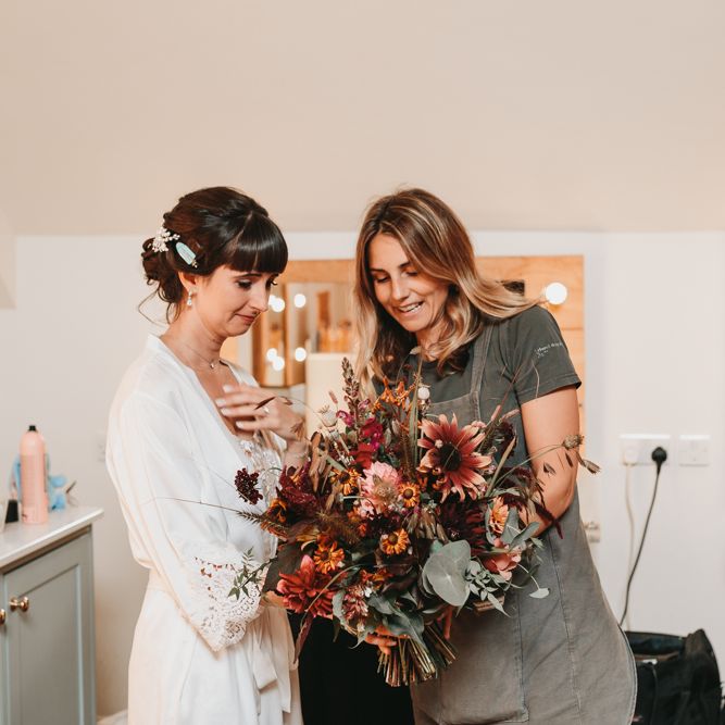 Bride on the wedding morning looking at her autumn wedding bouquet 