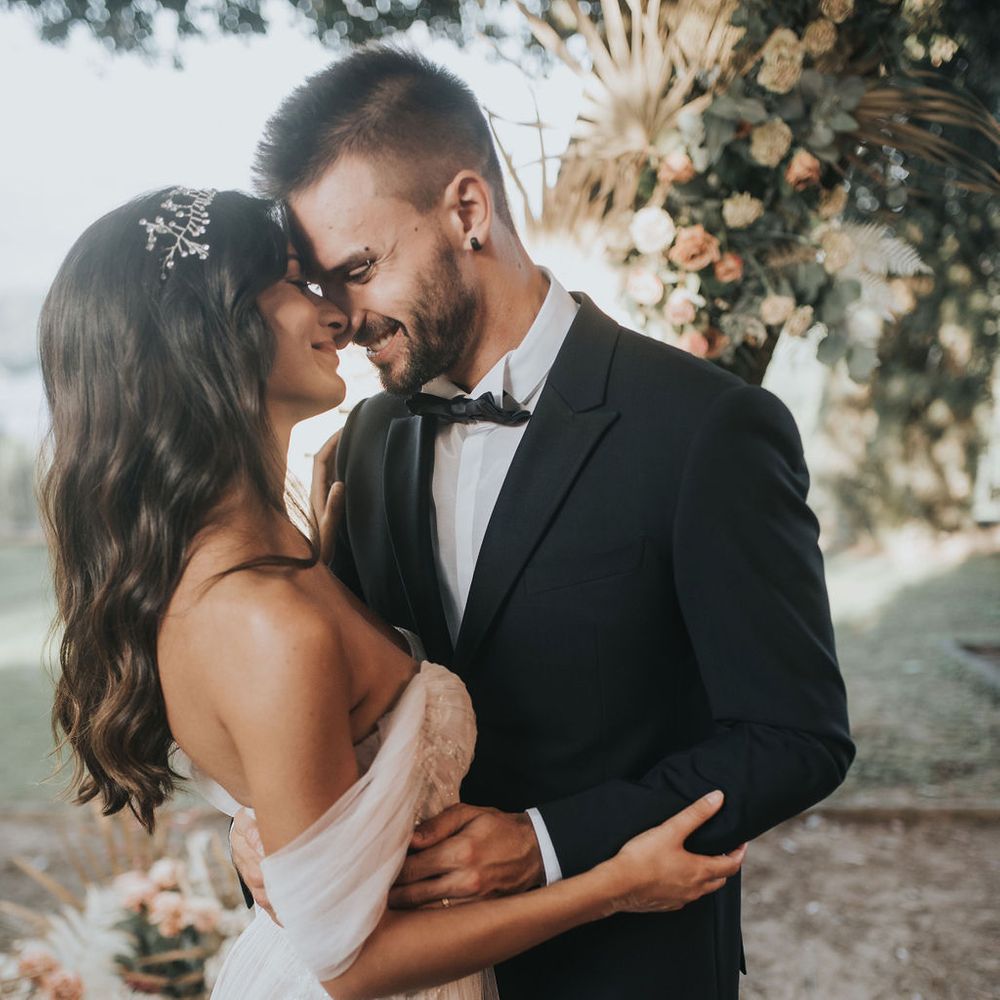 Groom in tuxedo and bride in romantic off the shoulder wedding dress