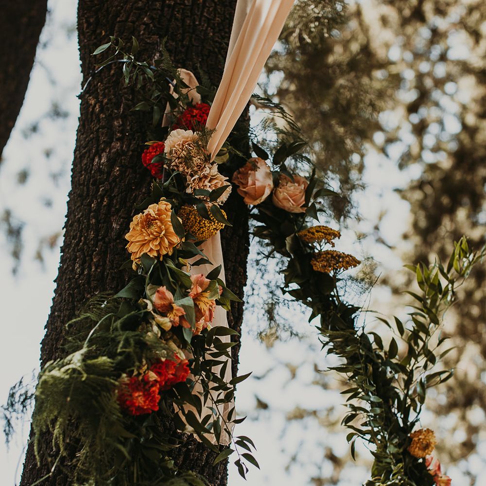 Orange and yellow wedding flowers with foliage decorating the trees at Andalusia wedding