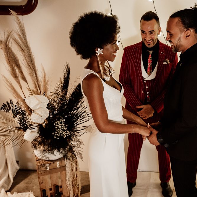 Bride in trousers and top with groom in black suit